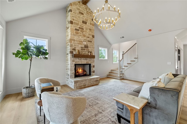 living room with high vaulted ceiling, a healthy amount of sunlight, a fireplace, and light hardwood / wood-style floors