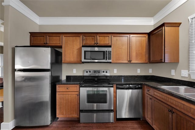 kitchen with sink, crown molding, dark stone counters, dark hardwood / wood-style flooring, and stainless steel appliances