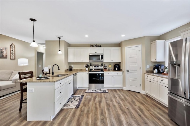 kitchen featuring white cabinetry, hanging light fixtures, sink, and appliances with stainless steel finishes