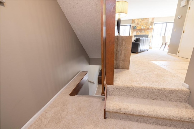 stairs with a stone fireplace and carpet