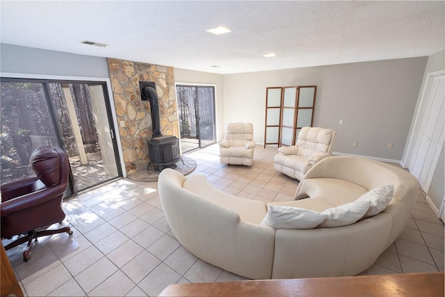 living room featuring light tile patterned floors, a wealth of natural light, a textured ceiling, and a wood stove