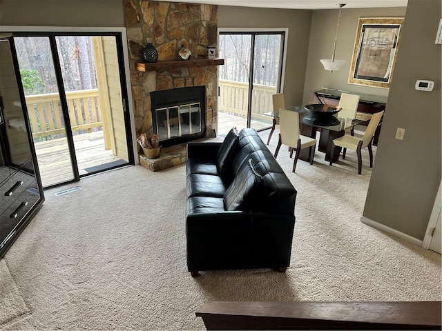 carpeted living room featuring a stone fireplace