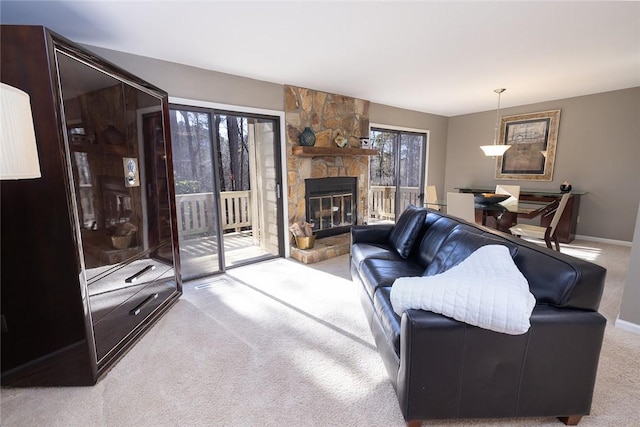 carpeted living room with a stone fireplace