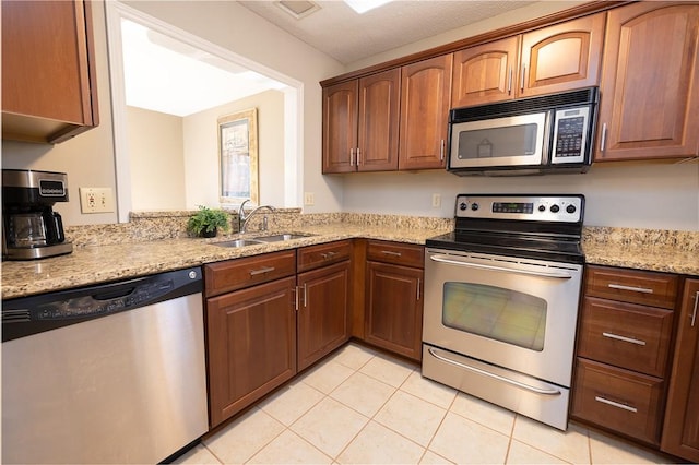 kitchen with light stone counters, sink, light tile patterned floors, and appliances with stainless steel finishes