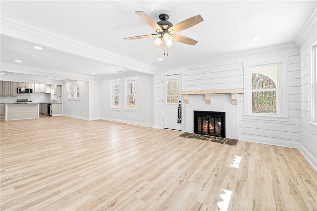 unfurnished living room featuring crown molding, a fireplace, and light wood-type flooring