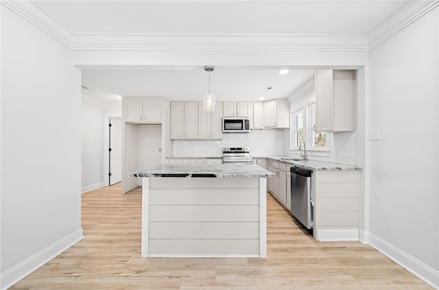 kitchen featuring a kitchen island, appliances with stainless steel finishes, pendant lighting, white cabinetry, and sink