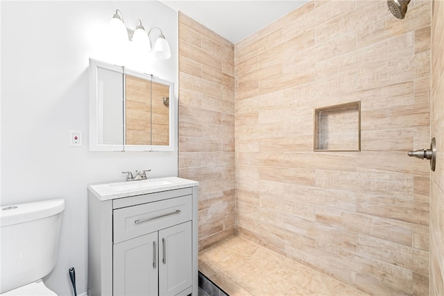 bathroom with vanity, a tile shower, and toilet