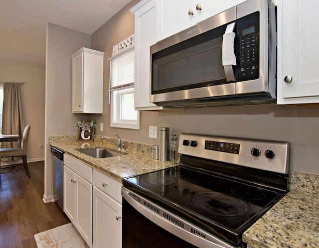 kitchen with appliances with stainless steel finishes, sink, white cabinets, and light stone counters