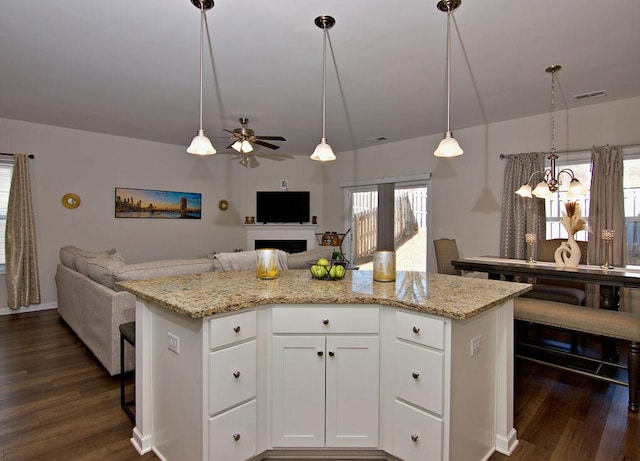 kitchen with a kitchen island, pendant lighting, white cabinets, and light stone counters