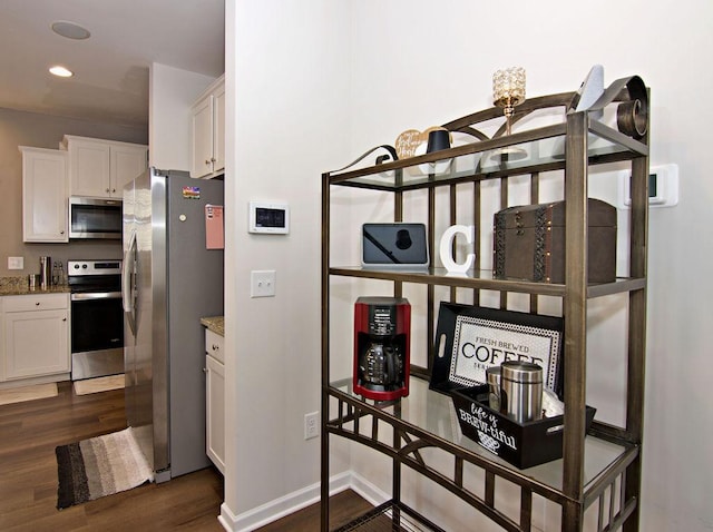 interior space featuring white cabinetry, stainless steel appliances, dark hardwood / wood-style flooring, and light stone countertops