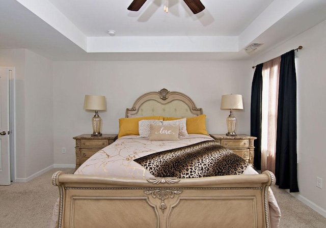 carpeted bedroom with a raised ceiling and ceiling fan