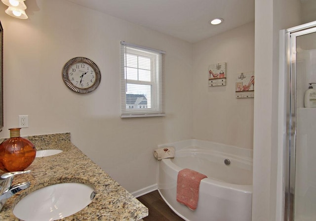 bathroom featuring vanity, wood-type flooring, and a tub