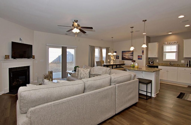 living room featuring dark wood-type flooring, sink, and ceiling fan