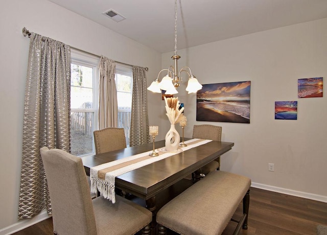 dining space featuring dark wood-type flooring and an inviting chandelier