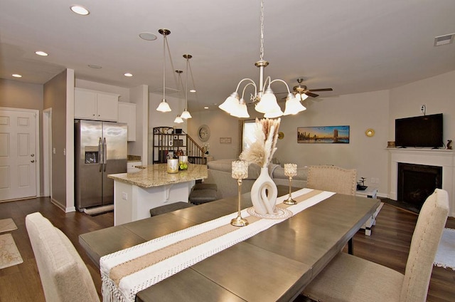 dining room with dark wood-type flooring and ceiling fan with notable chandelier