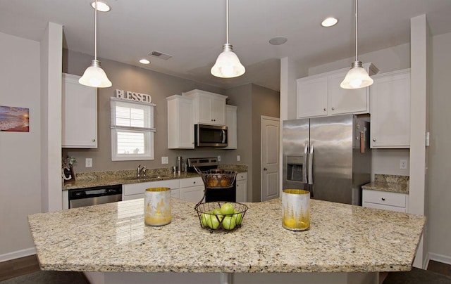 kitchen with white cabinetry, light stone counters, decorative light fixtures, a kitchen island, and stainless steel appliances