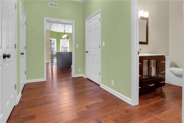 hall featuring dark wood-type flooring, sink, and a chandelier