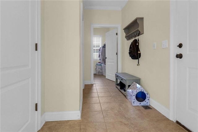 mudroom with crown molding and light tile patterned floors