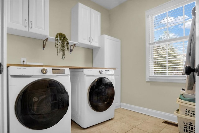 laundry room featuring separate washer and dryer, light tile patterned floors, and cabinets