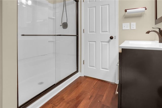 bathroom with wood-type flooring, a shower with shower door, and vanity