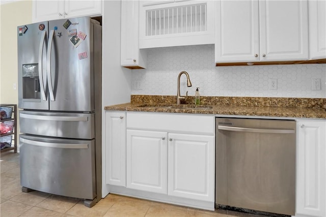 kitchen with appliances with stainless steel finishes, white cabinetry, sink, dark stone countertops, and decorative backsplash