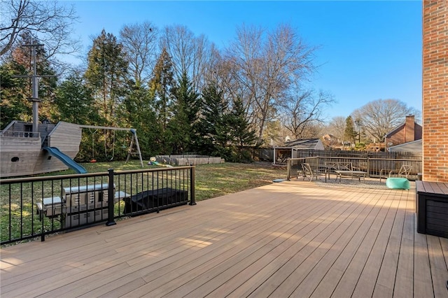 wooden deck featuring a playground and a lawn