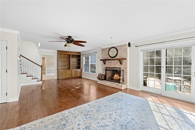 unfurnished living room featuring built in features, a fireplace, ornamental molding, and wood-type flooring