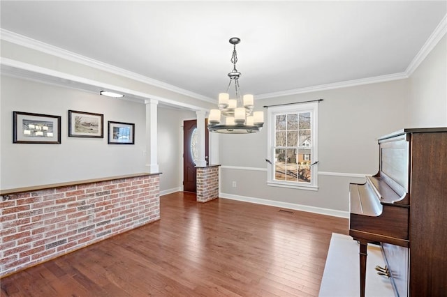 unfurnished dining area with crown molding, brick wall, a chandelier, and dark hardwood / wood-style flooring