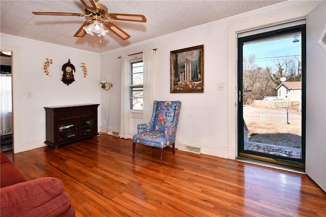 living area with crown molding, a textured ceiling, ceiling fan, and dark hardwood / wood-style flooring