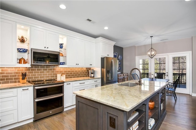 kitchen with sink, stainless steel appliances, white cabinets, and a center island with sink