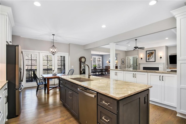 kitchen featuring sink, white cabinets, hanging light fixtures, stainless steel appliances, and a center island with sink