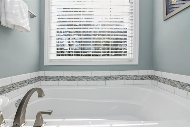 bathroom featuring a healthy amount of sunlight and tiled tub