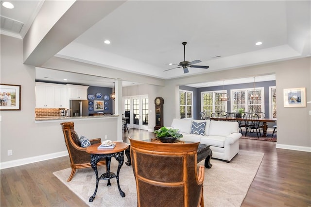 living room with a tray ceiling, wood-type flooring, and ceiling fan