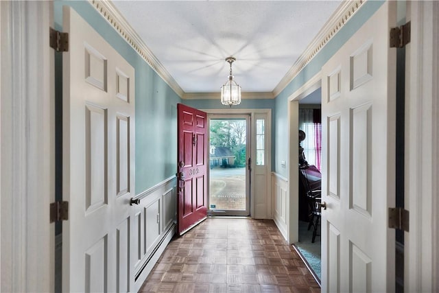 foyer featuring ornamental molding, a chandelier, dark parquet floors, and a baseboard heating unit