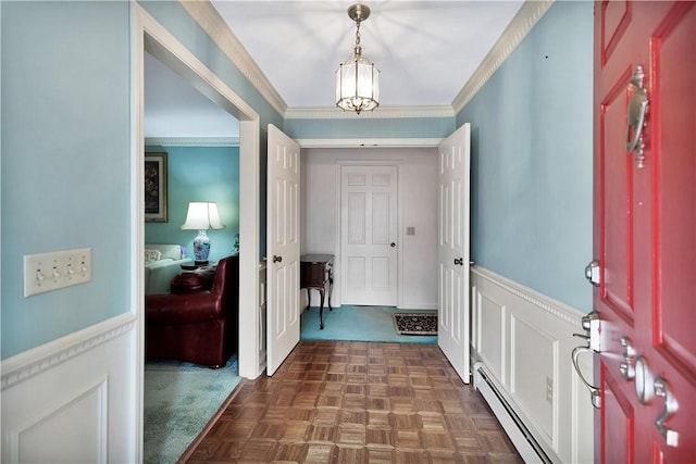 entrance foyer with baseboard heating, crown molding, a chandelier, and dark parquet floors