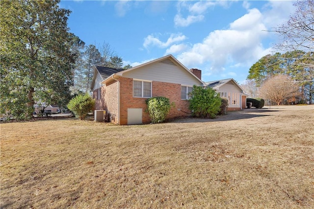 view of side of property featuring cooling unit and a yard