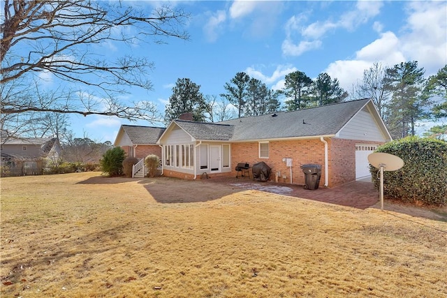 rear view of property featuring a garage, a sunroom, and a lawn