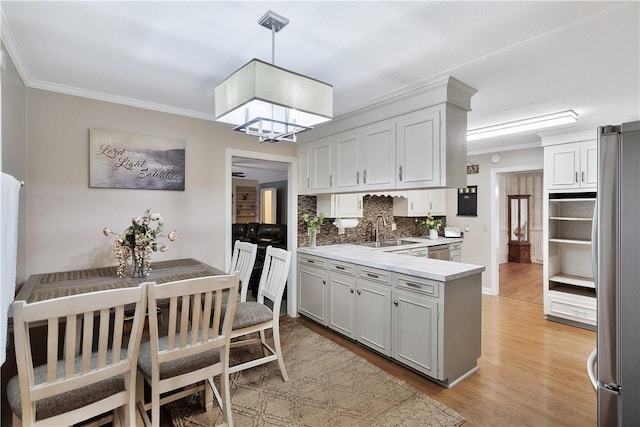 kitchen with pendant lighting, sink, stainless steel appliances, light hardwood / wood-style floors, and kitchen peninsula