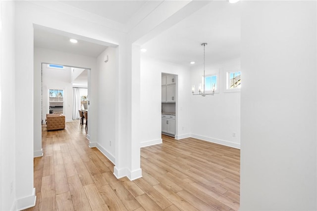 hallway featuring a notable chandelier and light hardwood / wood-style floors