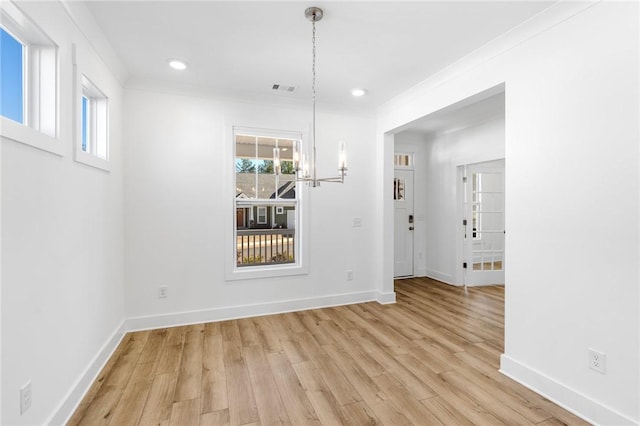 unfurnished dining area with ornamental molding, light hardwood / wood-style flooring, and a notable chandelier