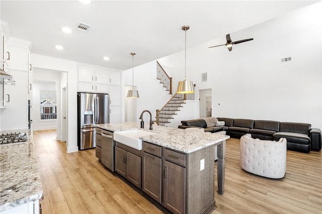 kitchen with sink, decorative light fixtures, stainless steel appliances, and white cabinets