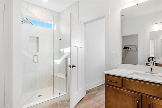 bathroom with hardwood / wood-style flooring, vanity, and walk in shower