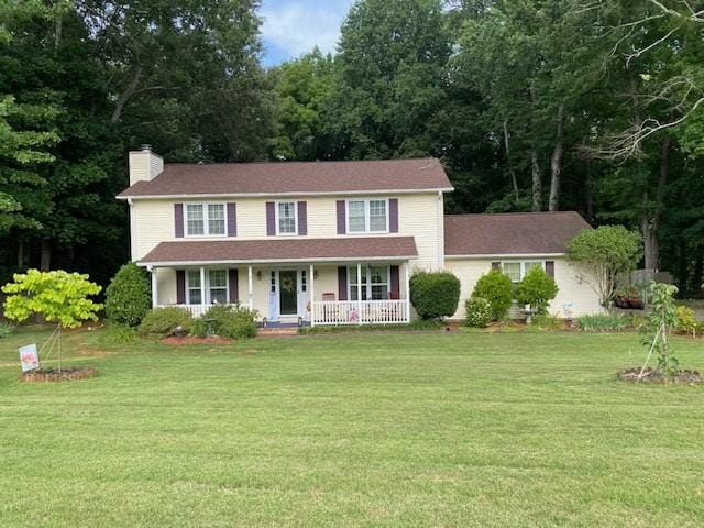 colonial home featuring a porch and a front yard