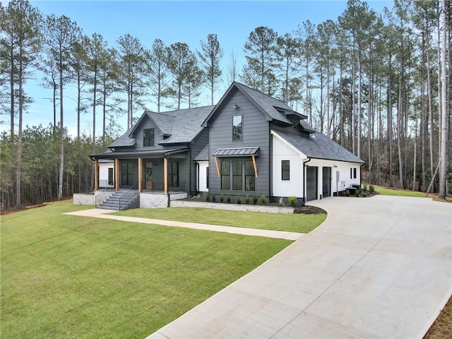 modern inspired farmhouse with a garage, a front yard, and covered porch