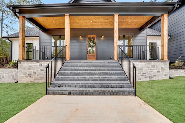 doorway to property featuring a porch and a yard