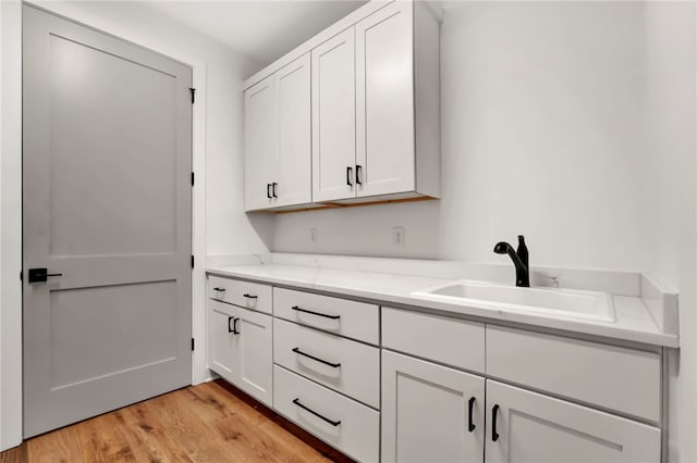 laundry area with sink and light hardwood / wood-style flooring