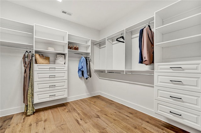 walk in closet with light hardwood / wood-style floors