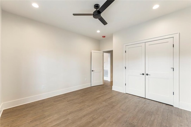 unfurnished bedroom featuring ceiling fan, a closet, and light wood-type flooring