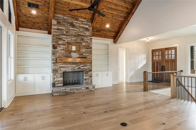 unfurnished living room featuring a stone fireplace, built in features, beamed ceiling, wood ceiling, and light hardwood / wood-style floors