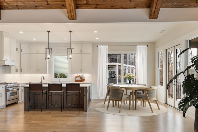 kitchen featuring white cabinetry, a center island, hanging light fixtures, beam ceiling, and high end stove